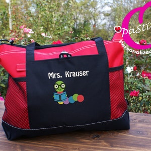 May include: Red and black tote bag with a mesh pocket. The bag is personalized with the text "Mrs. Krauser" and a cartoon worm reading a book.