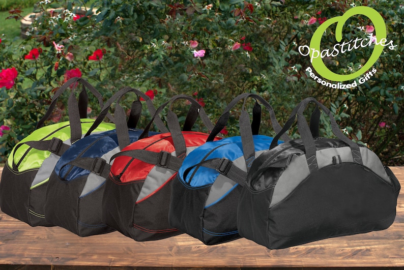 May include: Five duffel bags in different colours, each with black handles and straps. The bags are arranged on a wooden surface. All the bags are the same size and shape. They are made from a hard-wearing, water-resistant material. Opastitches Personalised Gifts.