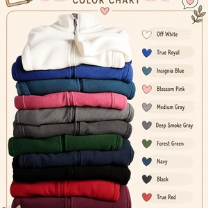 Puede incluir: Una pila de chaquetas de forro polar en varios colores, incluyendo blanco roto, azul real, azul insignia, rosa flor, gris medio, gris humo oscuro, verde bosque, azul marino, negro, rojo verdadero y granate, con una carta de colores.