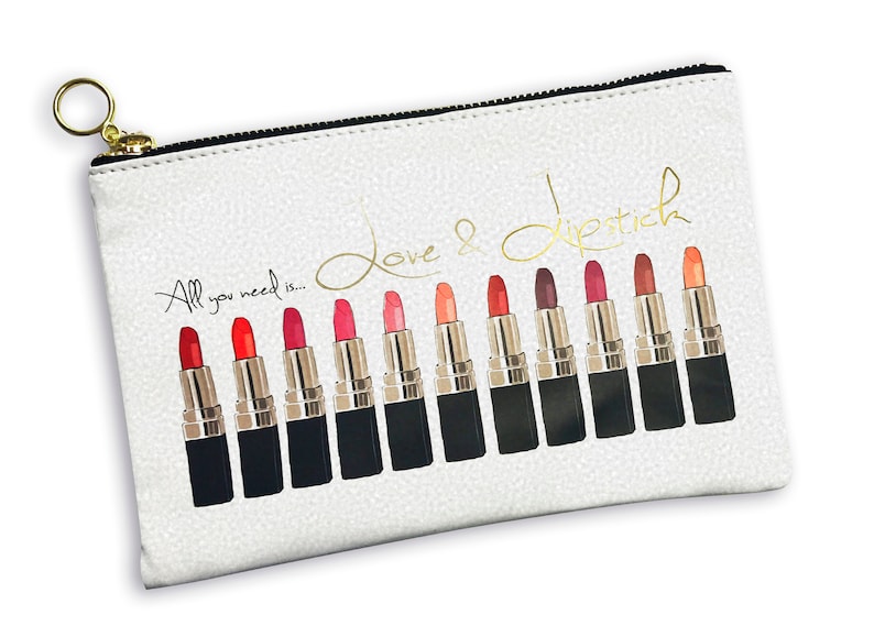 Pu&ograve; includere: Borsa bianca con cerniera e tiretto dorato. La borsa ha uno sfondo bianco con lettere dorate che dicono "Love & Lipstick" e "All you need is..." La borsa presenta una fila di 14 tubetti di rossetto in varie tonalit&agrave; di rosso, rosa e arancione.