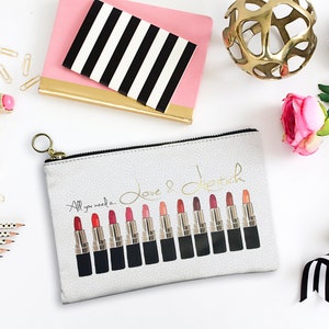 Pu&ograve; includere: Una pochette bianca con cerniera e un'iscrizione dorata che recita "Tutto ci&ograve; di cui hai bisogno &egrave; amore e rossetto". La pochette presenta una fila di 14 tubetti di rossetto con diverse tonalit&agrave; di rosso, rosa e nude.