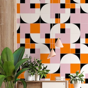 May include: A wall with a geometric pattern of pink, orange, black, and white squares and half circles. Two pendant lights with conical shades hang in front of the wall.