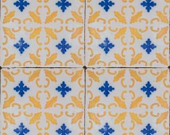 May include: Four square ceramic tiles with a repeating pattern of blue and yellow floral designs. The tiles are white with a yellow background and blue floral accents.