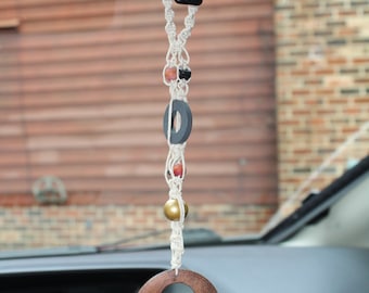 Pequeño adorno colgante de macramé con cáñamo natural y cuentas de madera de formas y colores únicos.
