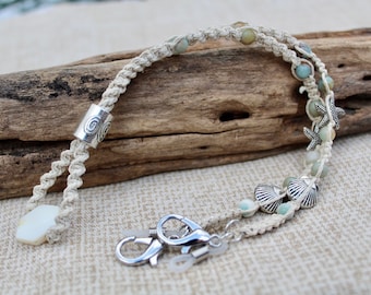 Porta gafas/mascarilla de concha de mar en macramé de cáñamo natural con dijes plateados y cuentas de cuarzo.