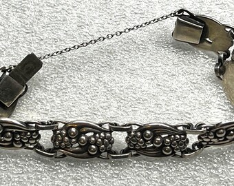 May include: Silver-toned bracelet featuring a series of beaded and oval-shaped links. The bracelet has a chain and clasp closure. The design incorporates a repeating pattern of beaded clusters and decorative oval links.