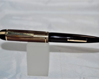 May include: A black and brown striped fountain pen with gold accents. The pen has a black cap and a gold band around the barrel.