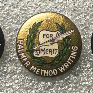 May include: Three round, blue and gold, vintage buttons with the text "Palmer Method" and a hand holding a pen. The gold button has a scroll with the text "For Merit" inside a wreath.