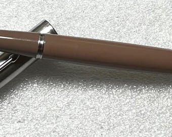 May include: A brown fountain pen with a silver cap and a silver clip. The pen is lying on a white surface.