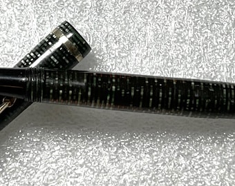 May include: A black and green fountain pen with a gold-toned nib and cap. The pen has a textured, speckled design.