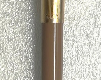 May include: A gold-colored pen with a brown barrel. The pen has a heart-shaped design on the clip and a textured top. The pen's tip is silver.