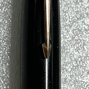 May include: Close-up of a black Parker pen with gold accents. The pen features a gold arrow clip and a gold band near the base. The top of the pen has the Parker logo and a blue accent.
