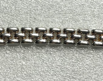 May include: A silver-toned metal watch band with a repeating pattern of rounded rectangular links. The band has a clasp at one end and is designed to be attached to a watch face. The band is approximately 7 inches long.