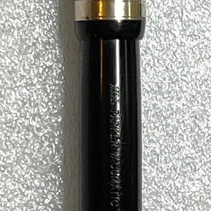 May include: A black fountain pen with gold-colored accents. The pen has a gold clip and a gold band near the center. The pen's nib is visible, and the pen's body has the text "PARKER VACUMATIC" printed on it.