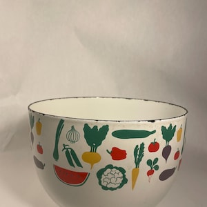 May include: White enamel bowl with a black rim, decorated with colorful illustrations of various vegetables. The bowl features images of tomatoes, carrots, and watermelon. A charming kitchenware item.