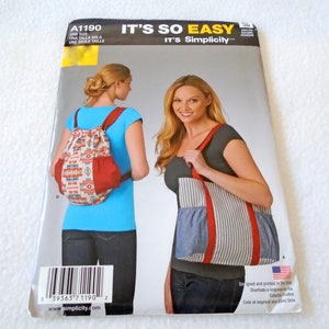 May include: A Simplicity sewing pattern for a drawstring backpack and a tote bag. The pattern is for one size and is designed and printed in the USA. The pattern shows two women wearing the bags. The backpack is red and white with a geometric pattern. The tote bag is blue and white striped with a red trim.