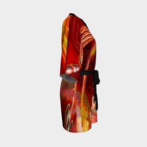 Puede incluir: Una bata de kimono de estampado abstracto rojo y amarillo con una faja negra. La bata tiene un dise&ntilde;o fluido y fluido.