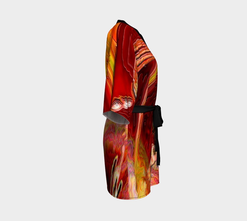 Puede incluir: Una bata de kimono de estampado abstracto rojo y amarillo con una faja negra. La bata tiene un dise&ntilde;o fluido y fluido.