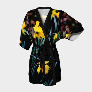 May include: A black kimono robe with a floral print of yellow daffodils on a dark background. The robe has a tie belt and short sleeves.