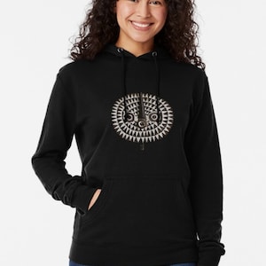 May include: A black lightweight hoodie with a white and gray geometric design on the front. The design features a circular pattern with a central eye shape.