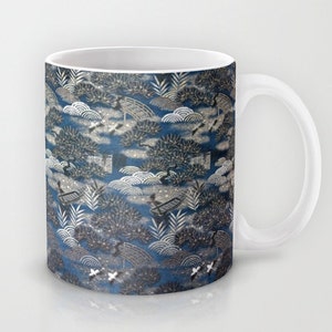 May include: A white ceramic mug with a blue and silver pattern. The pattern features stylized trees, clouds, and bridges.