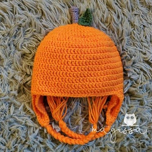 May include: Orange crocheted pumpkin hat with a green stem and long orange ties. The hat is made by magissa.