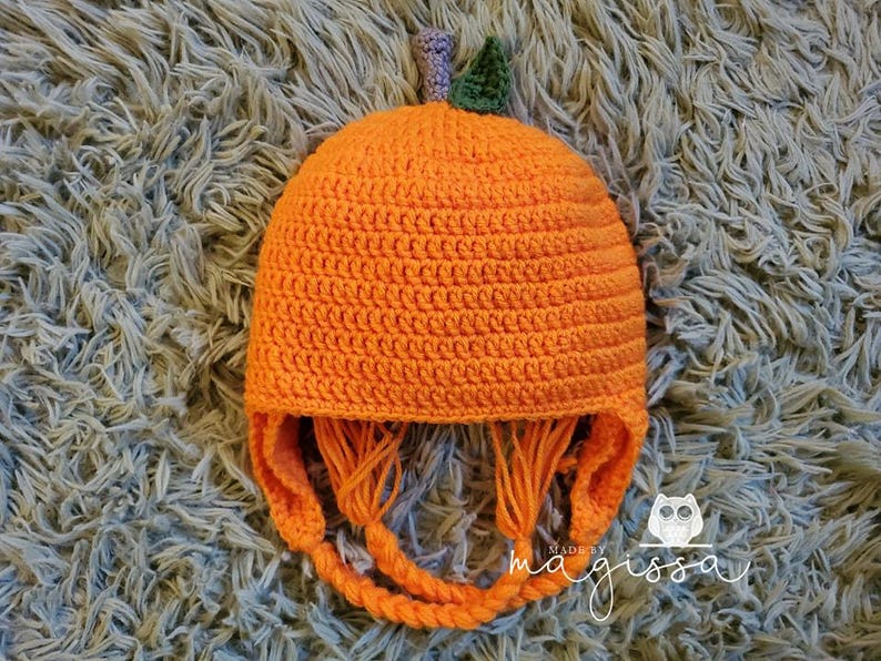May include: Orange crocheted pumpkin hat with a green stem and long orange ties. The hat is made by magissa.