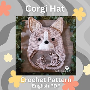 May include: A crocheted Corgi hat in tan, white, and black. The hat features large, upright ears and a white snout with a black nose. The hat has dangling tassels and the text "Corgi Hat" and "Crochet Pattern English PDF".
