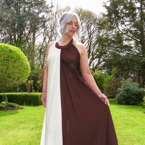 Puede incluir: Un vestido largo blanco y marrón con tirantes y un diseño sencillo. El vestido está hecho de una tela suave y fluida y tiene un corte holgado.