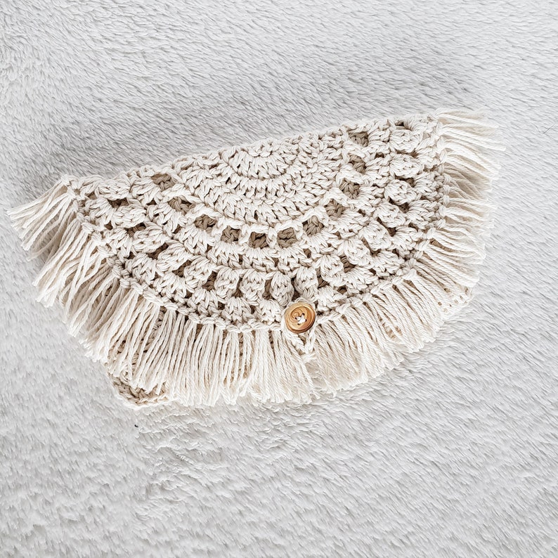 May include: A crocheted cream-colored collar with a fringe border and a wooden button.
