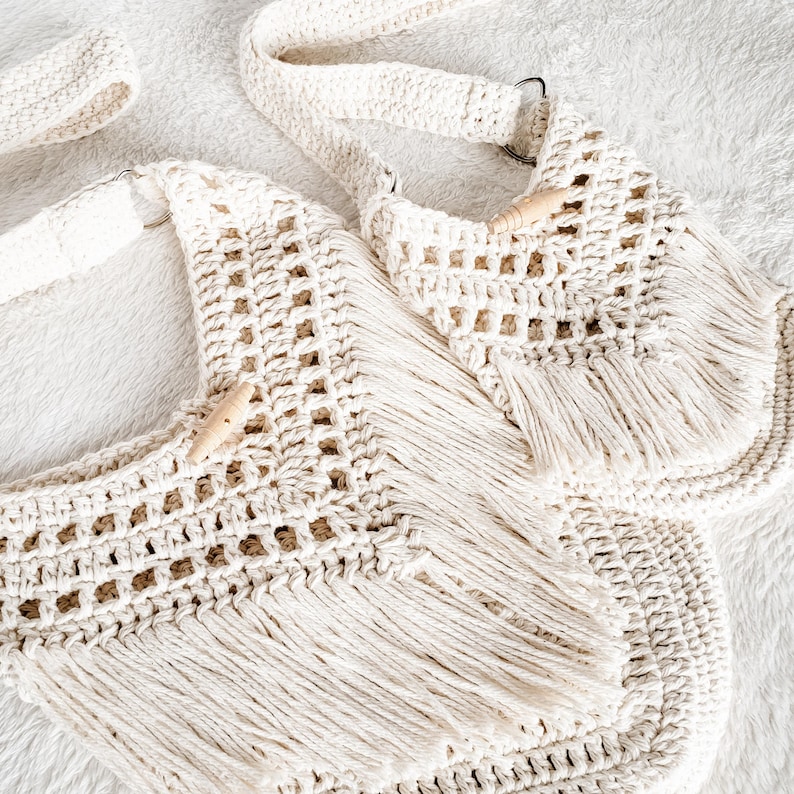 May include: Two crocheted bags with fringe detailing. The bags are made of natural white cotton yarn and have wooden toggles.
