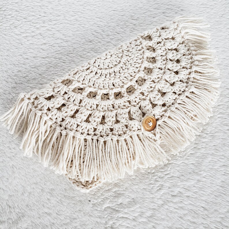 May include: A crocheted cream-colored shawl with a fringe border and a wooden button.