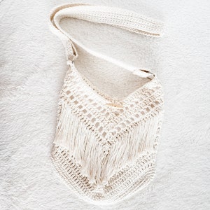 May include: A white crocheted bag with a long strap and fringe detail.