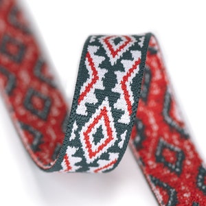 May include: Red and green patterned ribbon with a geometric design. The ribbon is woven with a white background and has a repeating pattern of diamonds and triangles.