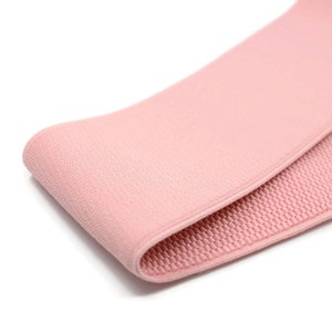 May include: Pink fabric resistance band with a smooth outer surface and a textured inner surface.
