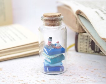 Books in a stack with miniature lighthouse and sailing boat in 6 cm glass bottle, miniature nautical scene, travel guide sea, sea,