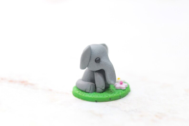 Miniatur Elefant aus Polymerclay, sitzend auf grünem Untergrund, Seitenansicht