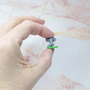 Miniatur Elefant aus Polymerclay, sitzend auf grünem Untergrund in der Hand