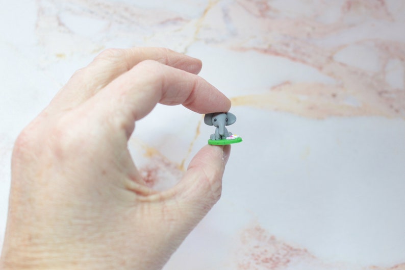 Miniatur Elefant aus Polymerclay, sitzend auf grünem Untergrund in der Hand