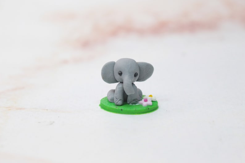 Miniatur Elefant aus Polymerclay, sitzend auf grünem Untergrund