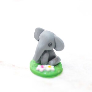 Miniatur Elefant aus Polymerclay, sitzend auf grünem Untergrund;Ansicht von rechts oben