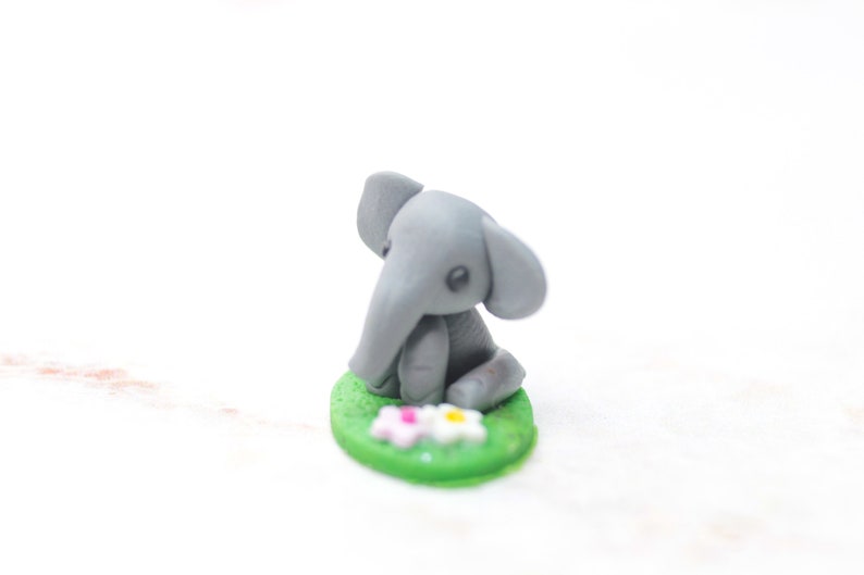 Miniatur Elefant aus Polymerclay, sitzend auf grünem Untergrund;Ansicht von rechts oben