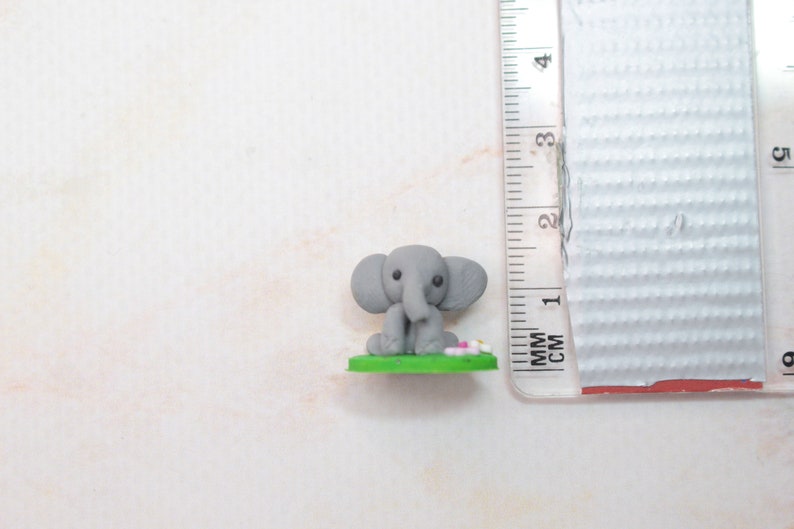 Miniatur Elefant aus Polymerclay, sitzend auf grünem Untergrund Vergleich mit cm Mass