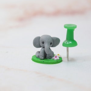 Größenvergleich mit Pin, Miniatur Elefant aus Polymerclay, sitzend auf grünem Untergrund