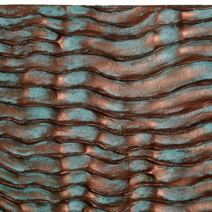 Puede incluir: Un panel de pared texturizado con un patr&oacute;n ondulado en tonos de turquesa y cobre.