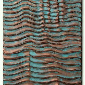 Puede incluir: Arte de pared abstracto con un patr&oacute;n ondulado texturizado en tonos de turquesa y cobre.