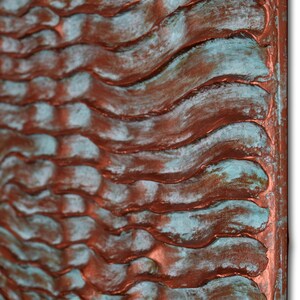 Puede incluir: Una escultura de pared de color cobre con una superficie ondulada y texturizada. La superficie tiene una p&aacute;tina azul verdosa.