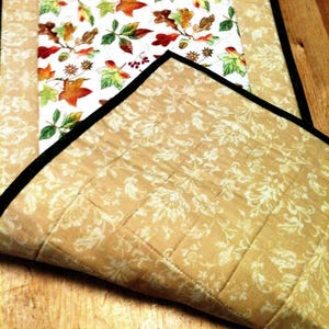 Pu&ograve; includere: Un runner da tavola trapuntato con un pannello centrale su sfondo bianco e un motivo colorato di foglie autunnali. I pannelli laterali sono in tessuto color cuoio con una stampa damascata floreale color crema. Il bordo &egrave; rifinito in nero.