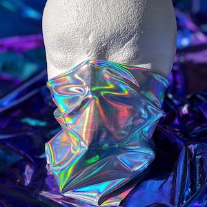 Silver holographic neck gaiter is wrapped around a white mannequin head reflecting rainbow colors from light shining on it.