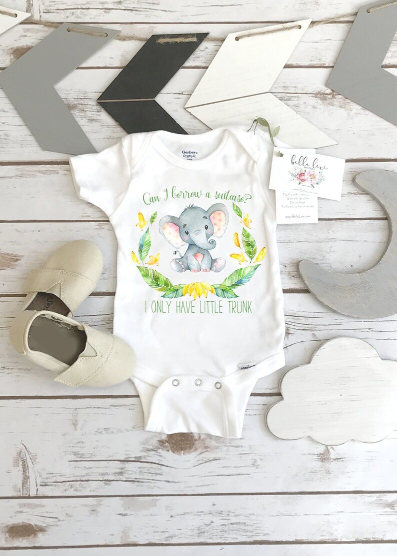 May include: White baby onesie with a watercolor illustration of a gray elephant with pink ears and a yellow flower crown. The onesie has the text "Can I borrow a suitcase? I only have little trunk."